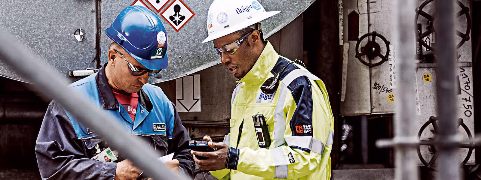 Two industrial workers in protective equipment checking a plant installation